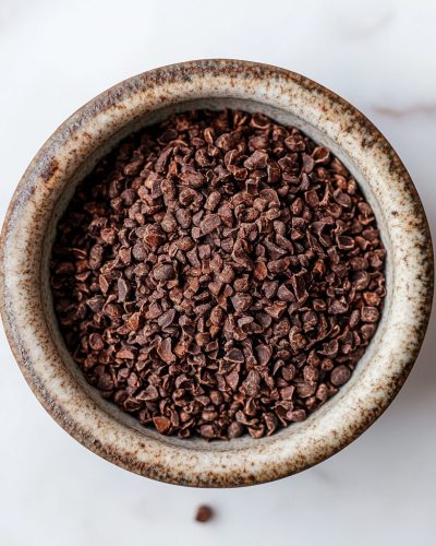 aviv8941_Ground_cocoa_beans_in_a_bowl_on_a_table_with_a_white_b_d2d576be-9139-4511-8294-2cb06dafea24